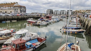 A marina with various boats docked, a building with multiple windows, and a clear sky. - Beachcombers, 13 Chesil House (Bridport)