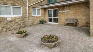 A courtyard with stone walls, a bench, and potted plants. - Beachcombers, 13 Chesil House (Bridport)