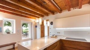 Une cuisine moderne avec des poutres en bois, un plan de travail blanc et une vue sur l’extérieur.