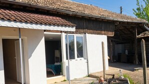 A white building with a tiled roof, a covered patio area, and a gravel pathway leading to the entrance. - Muddy Puddles Farm (Kovachevets)