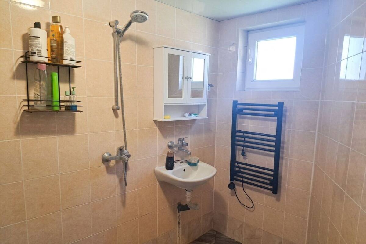 A bathroom with a shower, sink, cabinet, and towel rack.