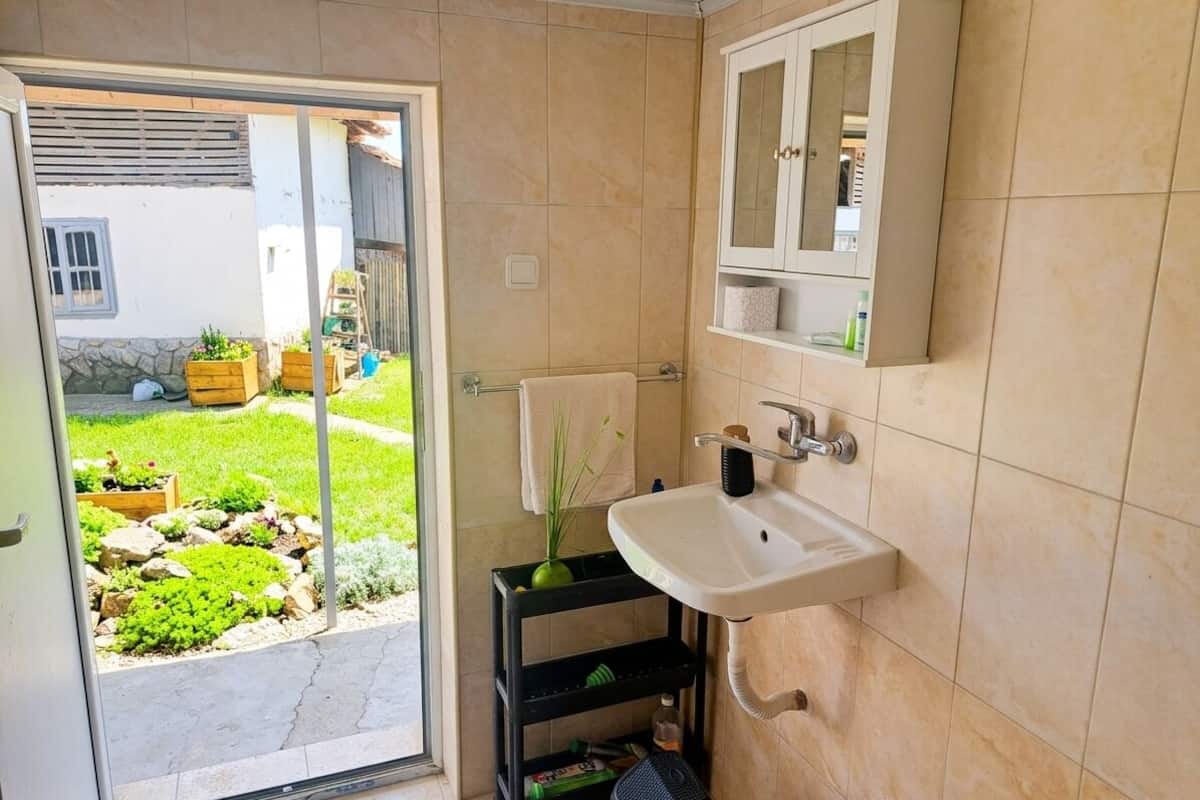 A bathroom with a white sink, a mirror cabinet, and a small shelf.
