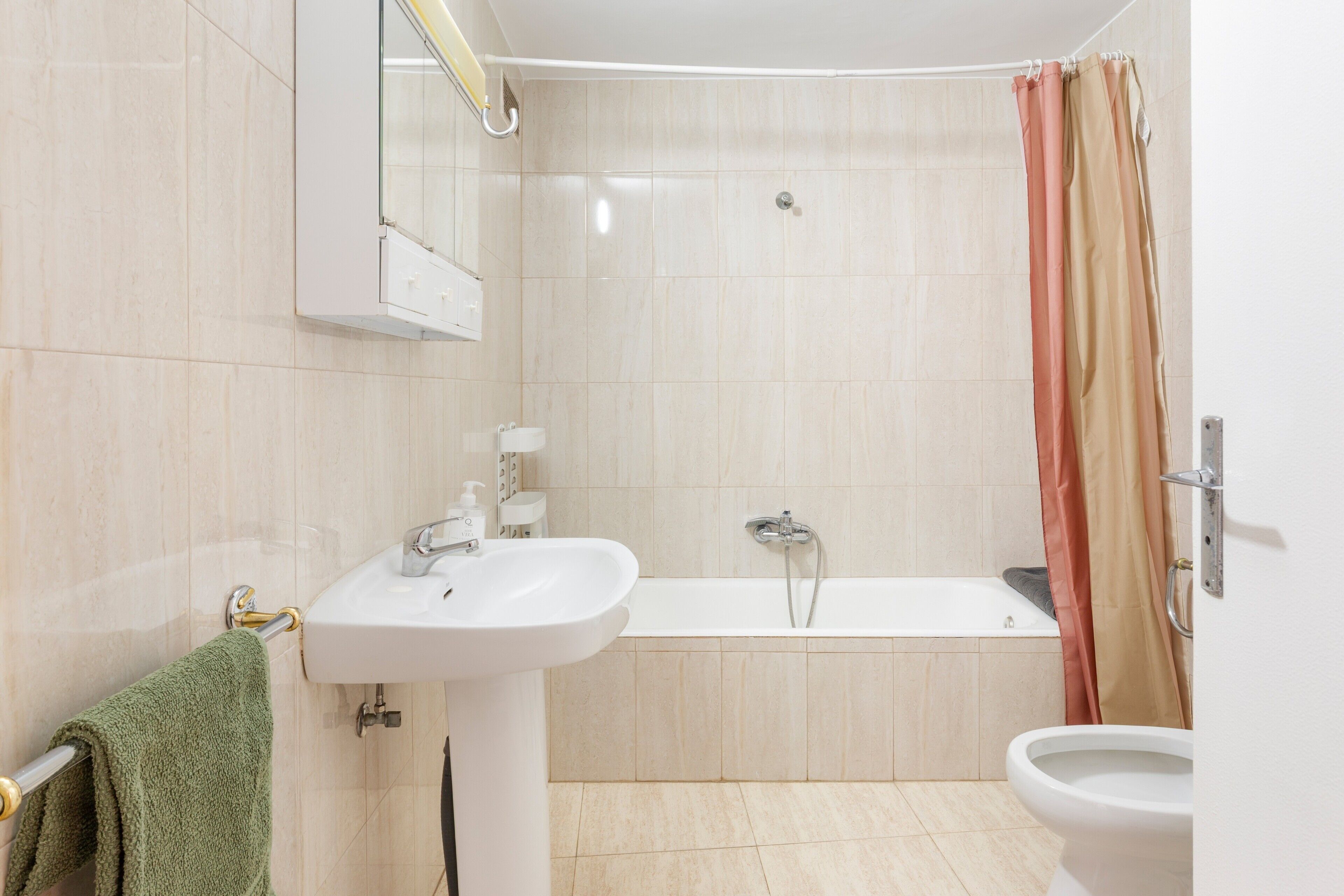 Un baño con lavabo, espejo, bañera y retrete.