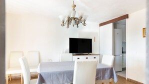 Un comedor con una mesa, sillas, una araña y un televisor.