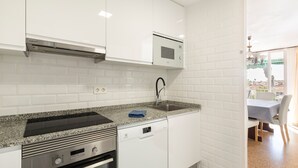 Una cocina moderna con armarios blancos, microondas integrado, estufa de acero inoxidable y lavavajillas.