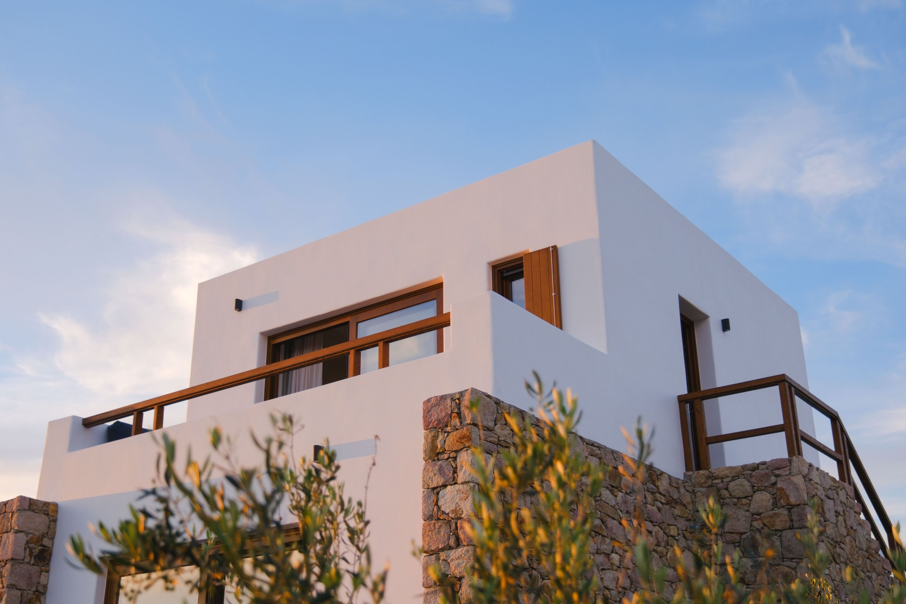 A modern building with a white exterior, wooden window frames, and a stone base.
