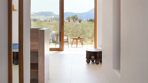 Un interior moderno con un espejo grande, vistas a un área de estar exterior a través de un ventanal y un diseño minimalista.