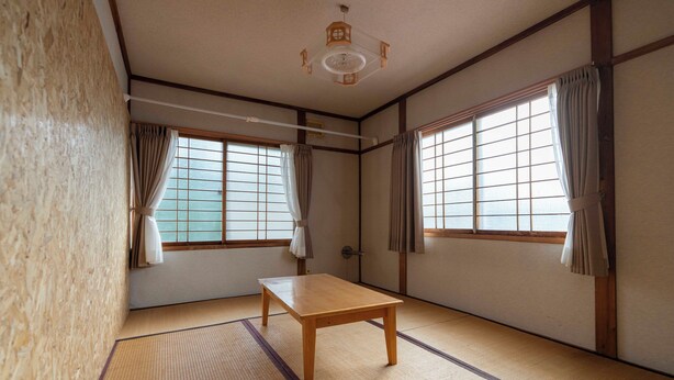 A traditional Japanese room with tatami flooring, a wooden table, sliding doors, and a ceiling fan. - One-room private inn Koropokkuru (中富良野町字中富良野東１線)