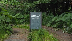 A sign with Japanese characters in a natural setting. - One-room private inn Koropokkuru (中富良野町字中富良野東１線)