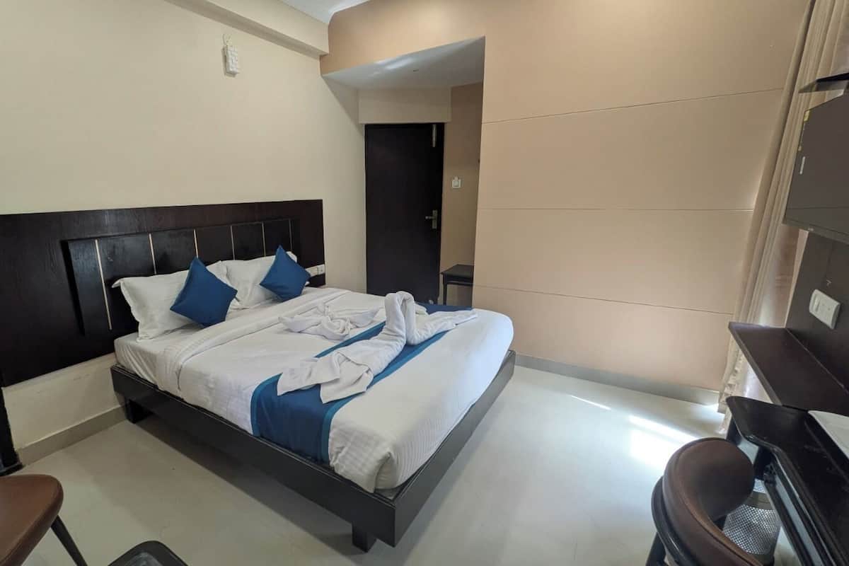 A hotel room with a bed, a chair, a desk, and a bathroom visible through an open door.
