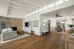 Uma sala de estar ampla com lareira, mesa de jantar e espaço de cozinha.