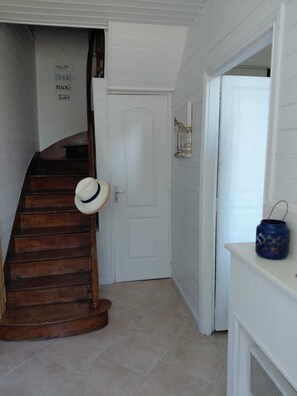 Una escalera con barandilla de madera y una puerta blanca al final.