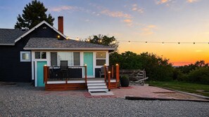 A small house with a porch, a staircase, and a string of lights. - Charming 3BR Farmhouse, Near Trails & Town (Fruita)