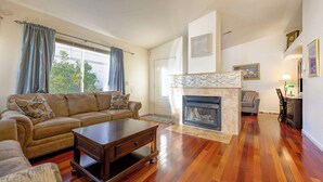 A living room with a sofa, coffee table, fireplace, and hardwood flooring.