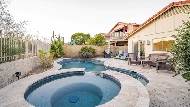 A backyard with a swimming pool, outdoor furniture, and a house with a balcony.