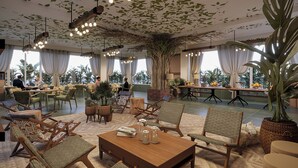 A spacious lounge area with comfortable seating, a large central table, and a ceiling adorned with hanging lights and greenery. - Brij Sone Bagh, Bandhavgarh | A Luxury Jungle Retreat (Umaria)