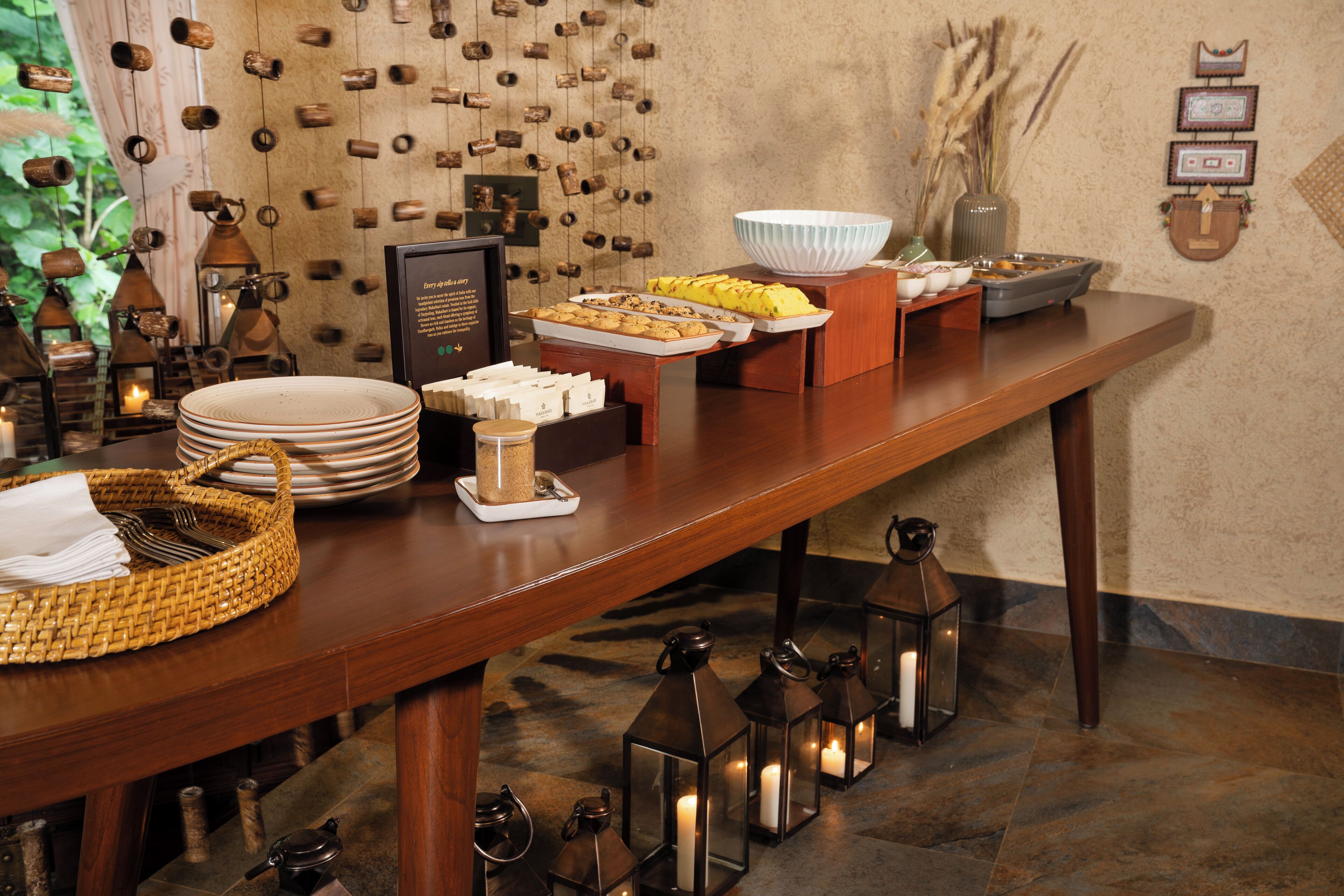 A buffet setup with various food items, a candle holder, and a decorative wall.