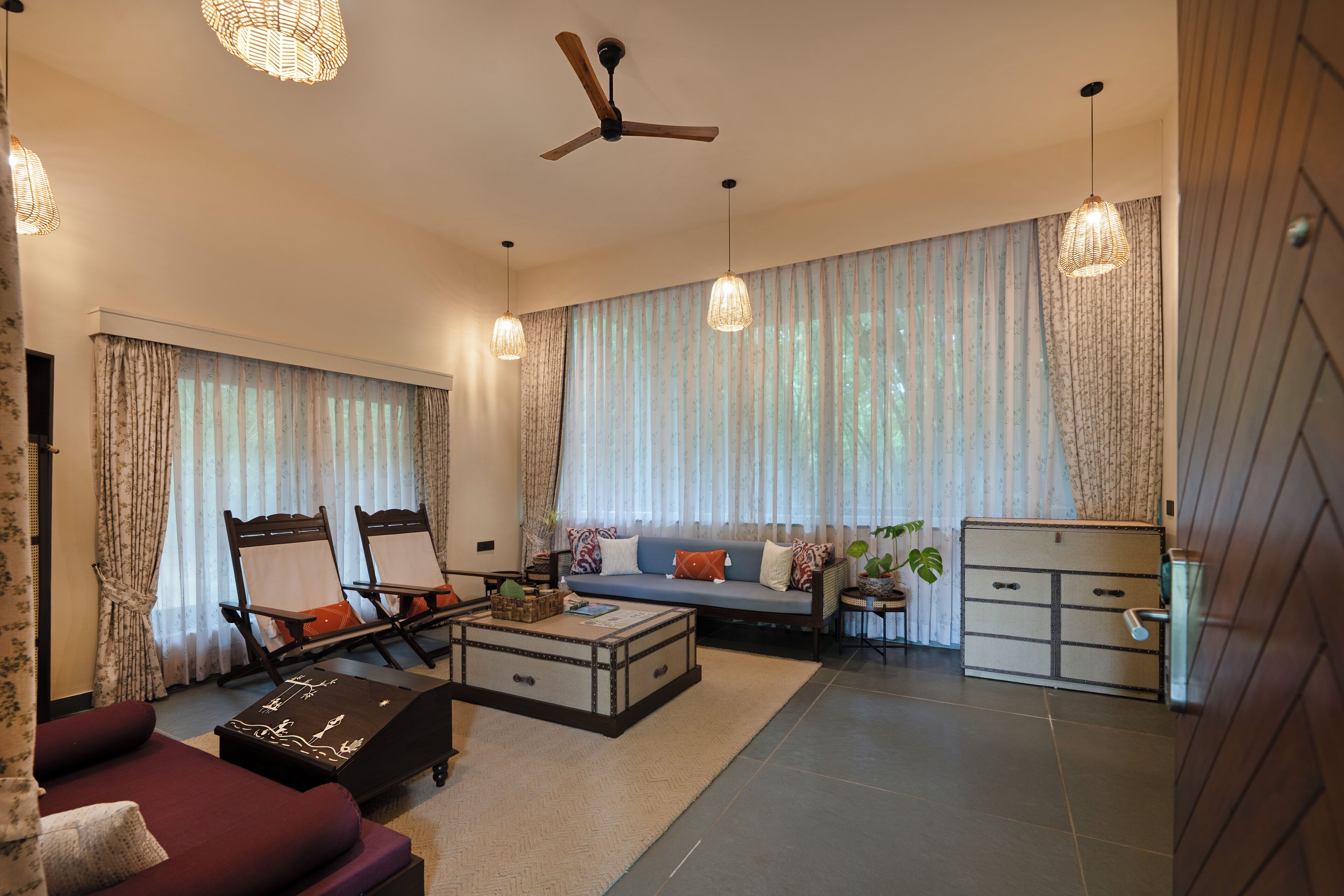 A modern living room with a sofa, two lounge chairs, a coffee table, and a ceiling fan.