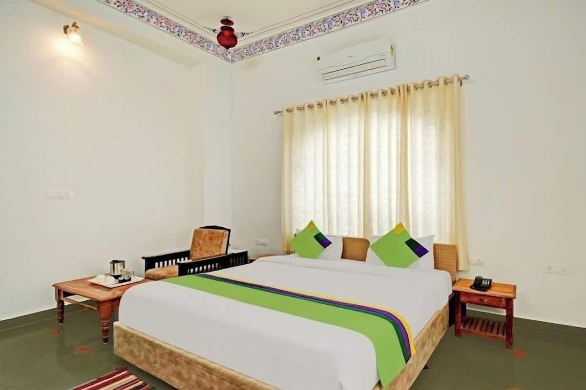 Une chambre d’hôtel avec un lit, une table de chevet, une chaise, une table et une fenêtre avec des rideaux.