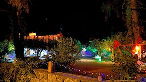 Un bâtiment aux fenêtres illuminées, avec un mur de pierre en premier plan.