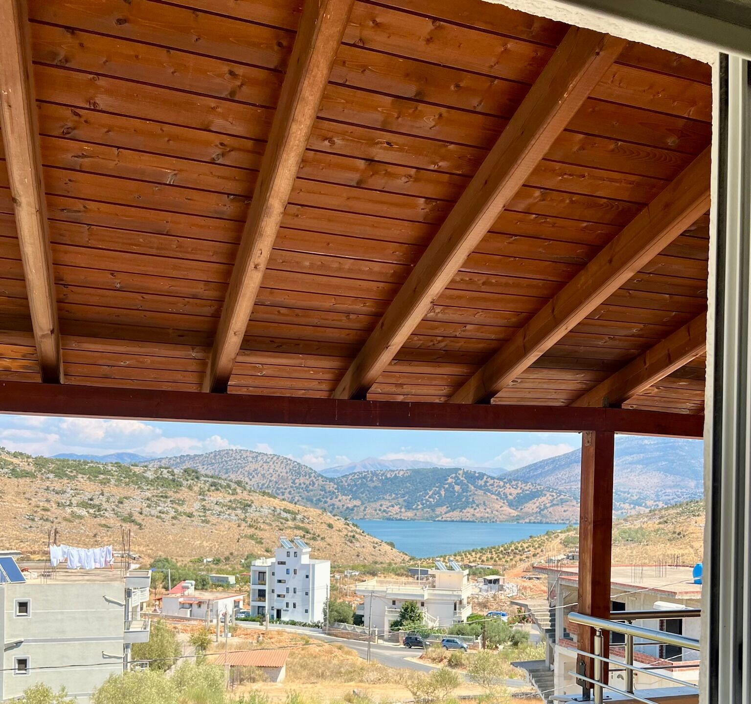 A wooden ceiling with a view of a mountainous landscape and a lake.