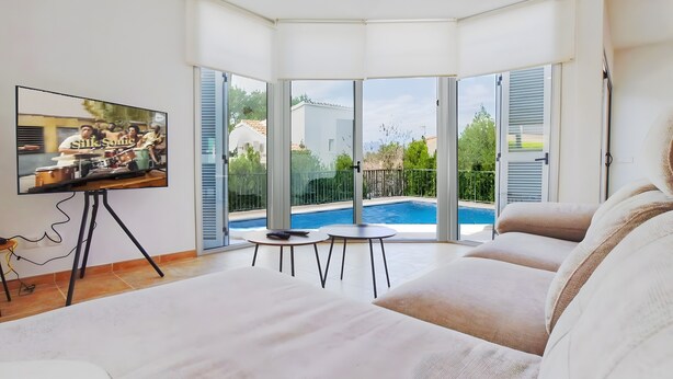 Ein modernes Zimmer mit großem Fernseher, Blick auf den Pool und einem Balkon.