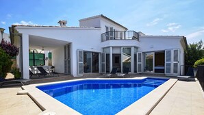 Ein modernes Haus mit Schwimmbad, großen Glasfenstern und einem Balkon.