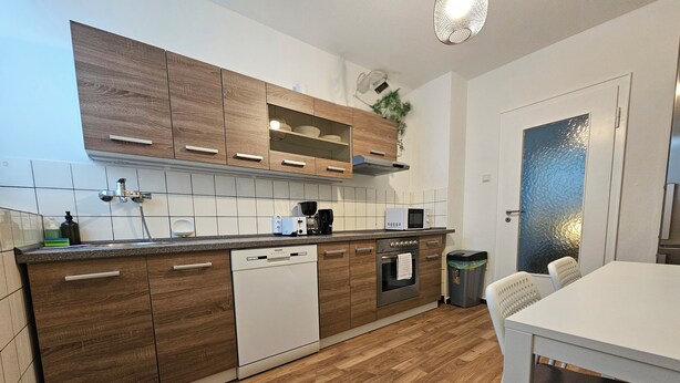 Una cucina moderna con mobili in legno, lavastoviglie, forno e microonde.