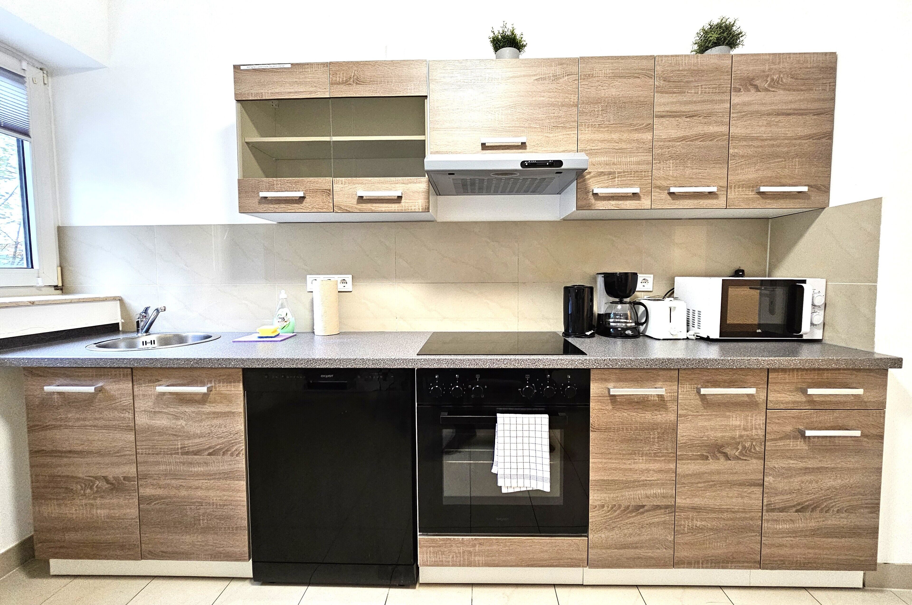Una cocina moderna con armarios de madera, lavavajillas, horno, microondas y cafetera.