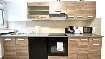 Una cocina moderna con armarios de madera, lavavajillas, horno, microondas y cafetera.