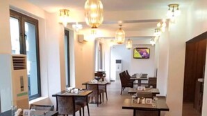 A modern dining area with multiple tables and chairs, ambient lighting, and a television screen on the wall. - Villa Angelia Hotel & Chinese Restaurant (Lagos)