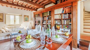 Ein Essbereich mit einem Holztisch, der für eine Mahlzeit gedeckt ist, umgeben von Bücherregalen voller Bücher.