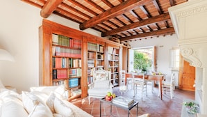 Ein gemütliches Wohnzimmer mit Kamin, Bücherregal und Essbereich mit Tisch und Stühlen.