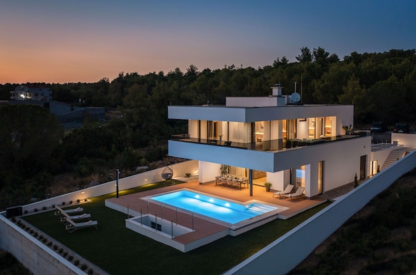 A modern two-story house with a swimming pool, outdoor seating, and a view of the surrounding forest. - Villa Calvi Zadarvillas (Zadar)