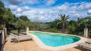 A swimming pool with lounge chairs, surrounded by a brick patio and a metal fence. - Villa 'Es Galliner' with Private Pool, Private Terrace and Wi-Fi (Illes Balears)