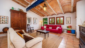 A living room with a high ceiling, wooden beams, a red sofa, a beige sofa, a wooden cabinet, and a small table. - Villa 'Es Galliner' with Private Pool, Private Terrace and Wi-Fi (Illes Balears)