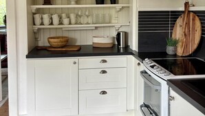 Una cocina con muebles blancos, encimera negra y suelo a cuadros.