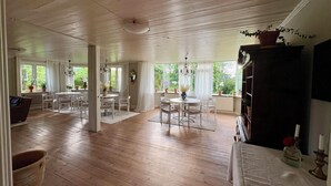 Una habitación amplia con piso de madera, un área de comedor con mobiliario blanco y una estantería.