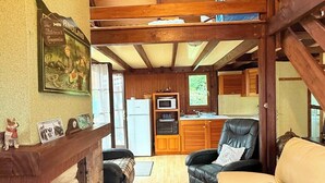 A cozy living room with a wooden staircase, a sofa, and a kitchen in the background.