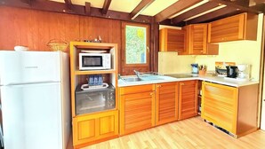 A compact kitchen with wooden cabinets, a microwave, a refrigerator, and a sink.