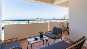 A balcony with wicker furniture, a glass table, and a view of the sea. - Bayview 2-BR Apartment in Larnaca (Larnaca)