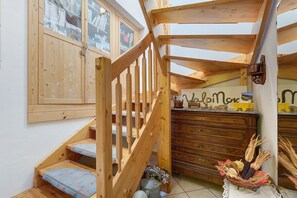 A wooden staircase with a handrail, a wooden cabinet with glass doors, and a small table with decorative items.