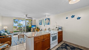 A kitchen with wooden cabinets, a white stove, and a dining area with a table and chairs. - Unwind in Napili, as sunsets await (Napili)