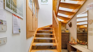 A wooden staircase with a wooden railing, a wall-mounted light switch, and a wooden cabinet. - Apartment 'Odorizzi Lago Di Tovel' with Mountain View and Shared Garden (Tassullo)