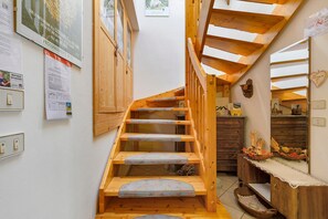 A wooden staircase with a wooden railing, a wall-mounted light switch, and a wooden cabinet.