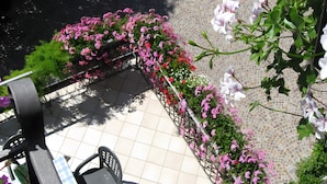 A tiled patio with a metal railing, surrounded by flowering plants. - Apartment 'Odorizzi Lago Di Tovel' with Mountain View and Shared Garden (Tassullo)