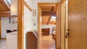 A wooden interior with a kitchen area, a wooden dresser, and a bedroom with a bed and dresser. - Apartment 'Odorizzi Lago Di Tovel' with Mountain View and Shared Garden (Tassullo)