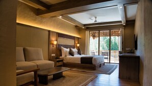 A spacious bedroom with a large bed, a sofa, a desk, and a balcony with a view. - Hotel Stendel (Diskit)