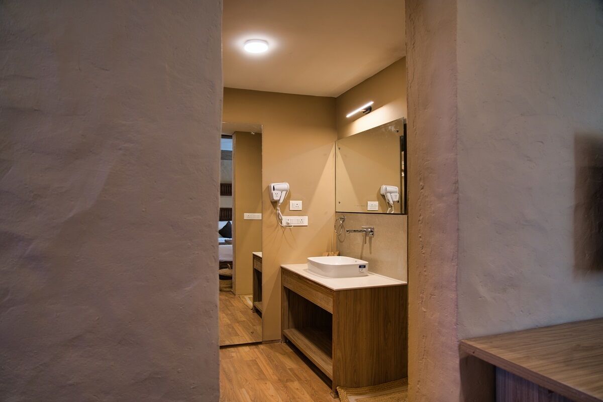 A modern bathroom with a wooden vanity, a white sink, and a large mirror.