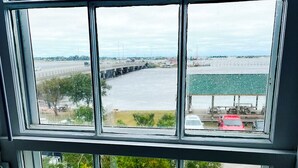 A view through a window with a clear sky, a bridge, and a parking lot with a red car. - Historical Mattocks House - Waterfront, Downtown Swansboro, Boat Slip (Swansboro)